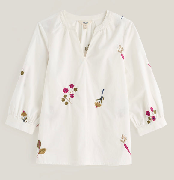 A white Seasalt long sleeve blouse with delicate floral and botanical embroidery in pink, green, and brown, displayed on a neutral light grey background.