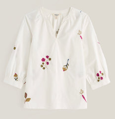 A white Seasalt long sleeve blouse with delicate floral and botanical embroidery in pink, green, and brown, displayed on a neutral light grey background.