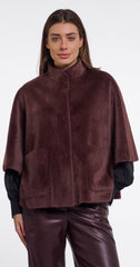 A woman wearing Rino & Pelle dark brown faux fur cape jacket with a high collar and front pockets, paired with black long sleeves and dark brown faux leather pants, against a plain white background.