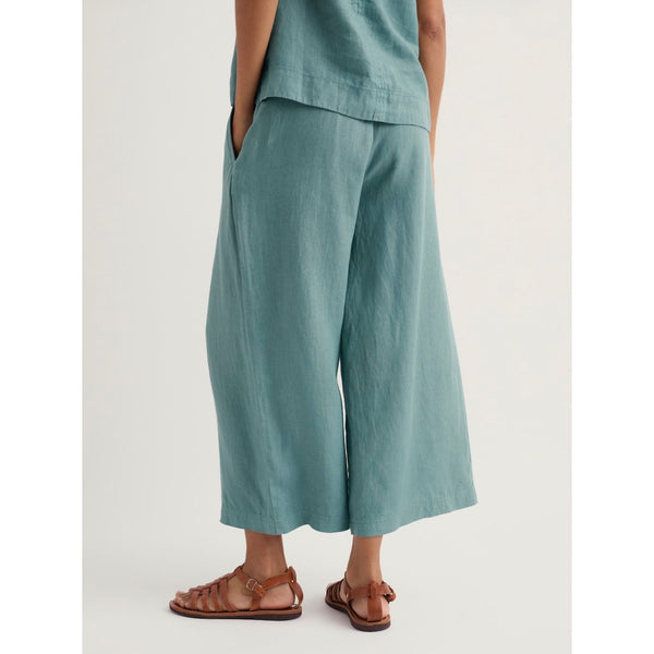 Woman wearing teal cropped short wide leg pants on a white background.