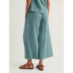Woman wearing teal cropped short wide leg pants on a white background.