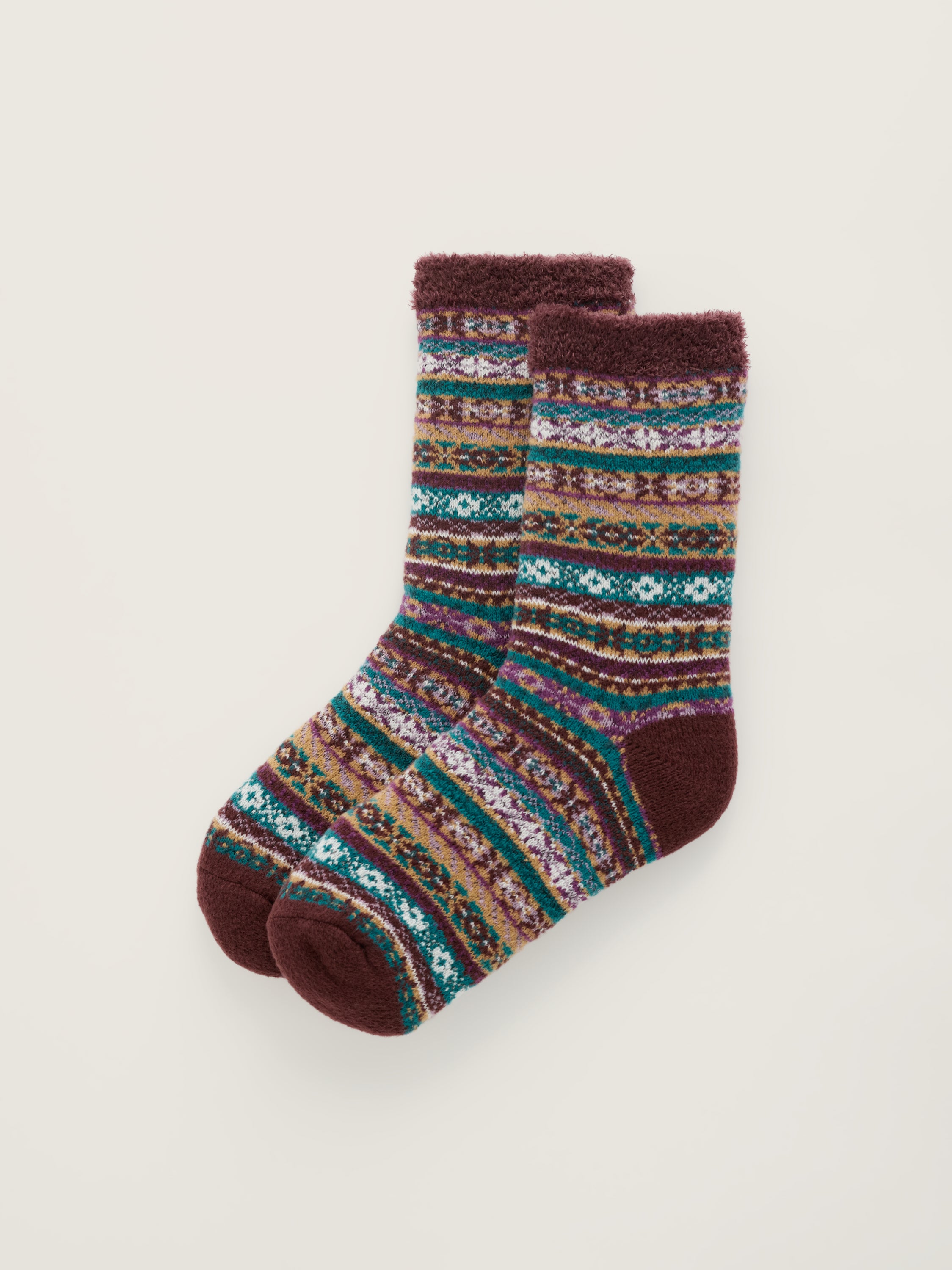 A pair of plush Seasalt cabin socks with a multicolor Fair Isle pattern and, heels, and toes, displayed on a light beige background.