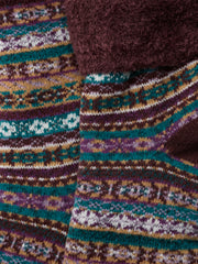 Close-up of a Seaslt sock textile with a multicolor Fair Isle pattern in teal, purple, brown, beige, and white, layered over a dark brown plush fleece fabric.