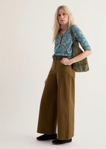 Seasalt 3/4 sleeve button front top in a dusty blue fabric with a dense yellow and orange floral print, laid flat against a light beige background.