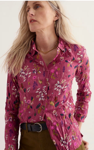 A dusty pink cotton with a colourful floral and butterfly print, styled in a twisted knot on a plain off-white background.