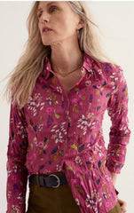 A woman modelling a Seasalt Larissa Shirt in pink floral pattern, with olive trousers and black belt against a off white background.