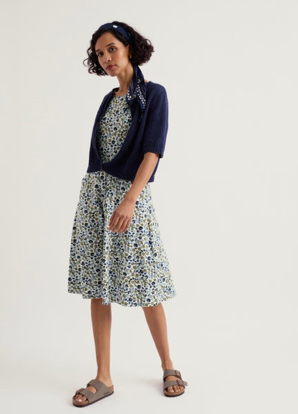 Woman wearing a floral dress with a navy cardigan on a white background