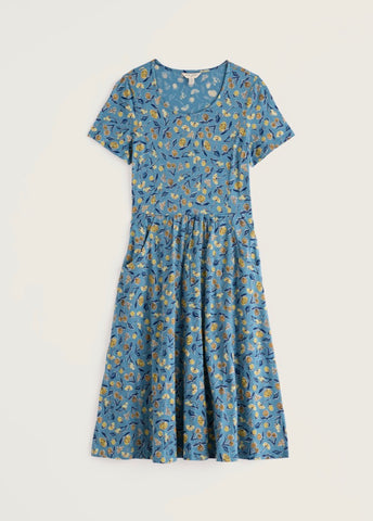 A close up of a blue fabric with a repeating floral pattern in yellow and navy blue.