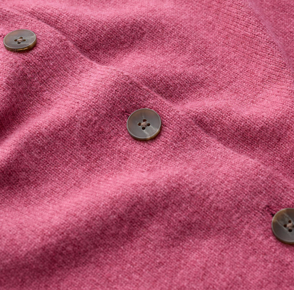 Close up Seasalt pink knit fabric with three visible brown buttons on a soft, textured surface.