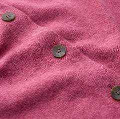 Close up Seasalt pink knit fabric with three visible brown buttons on a soft, textured surface.