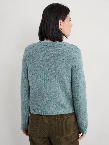 Woman wearing a teal knitted sweater against a plain background