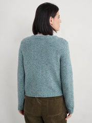 Woman wearing a teal knitted sweater against a plain background