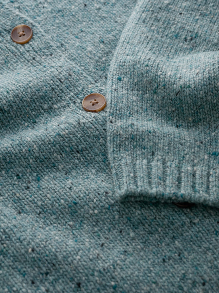 Close-up of a textured teal fabric cardigan with buttons