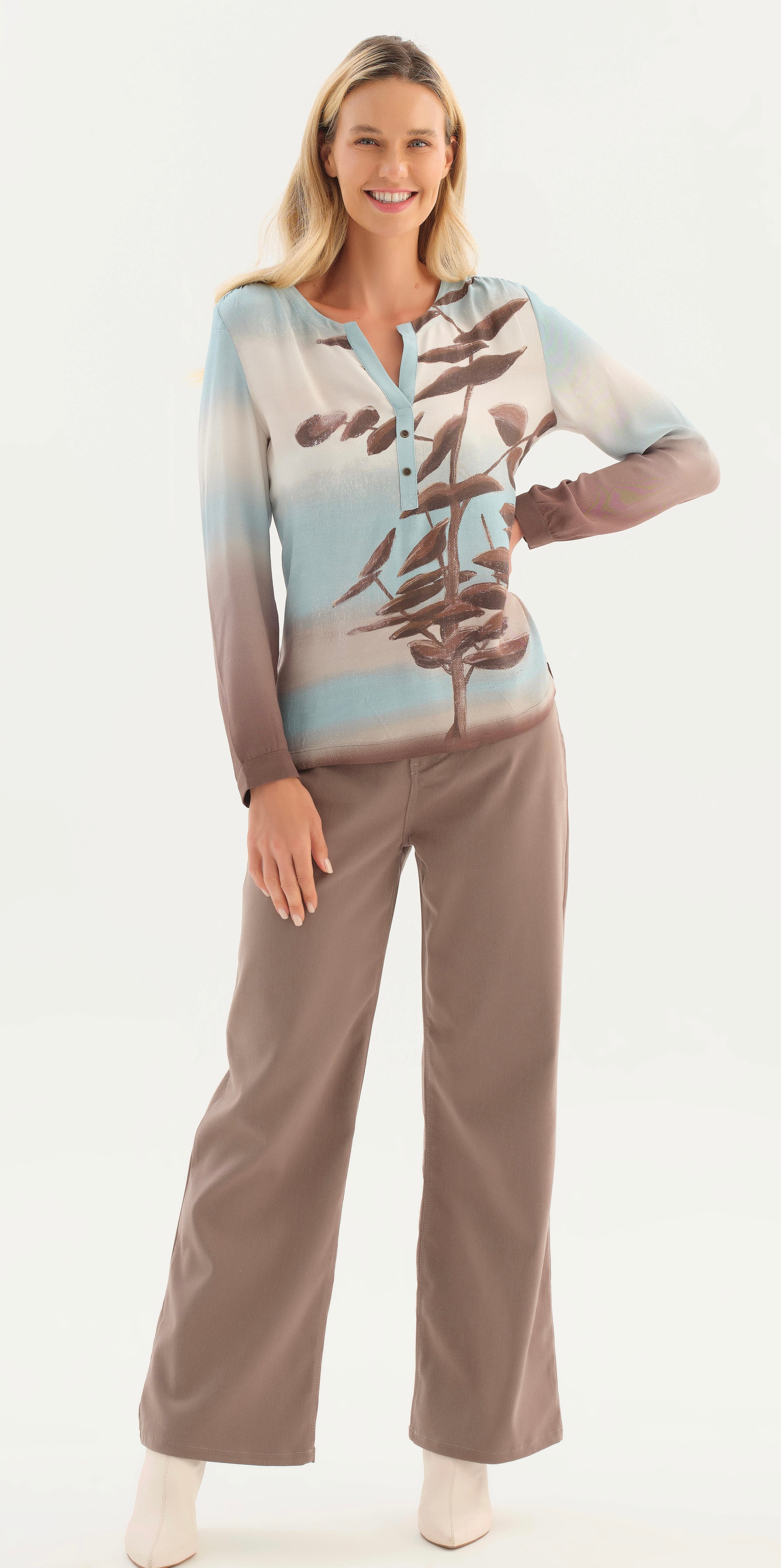 A woman modelling a two-piece lounge set featuring Dolcezza long-sleeve button-up top with a blue, beige, and brown gradient and branch print, paired with matching wide-leg pants, against a plain white studio background.