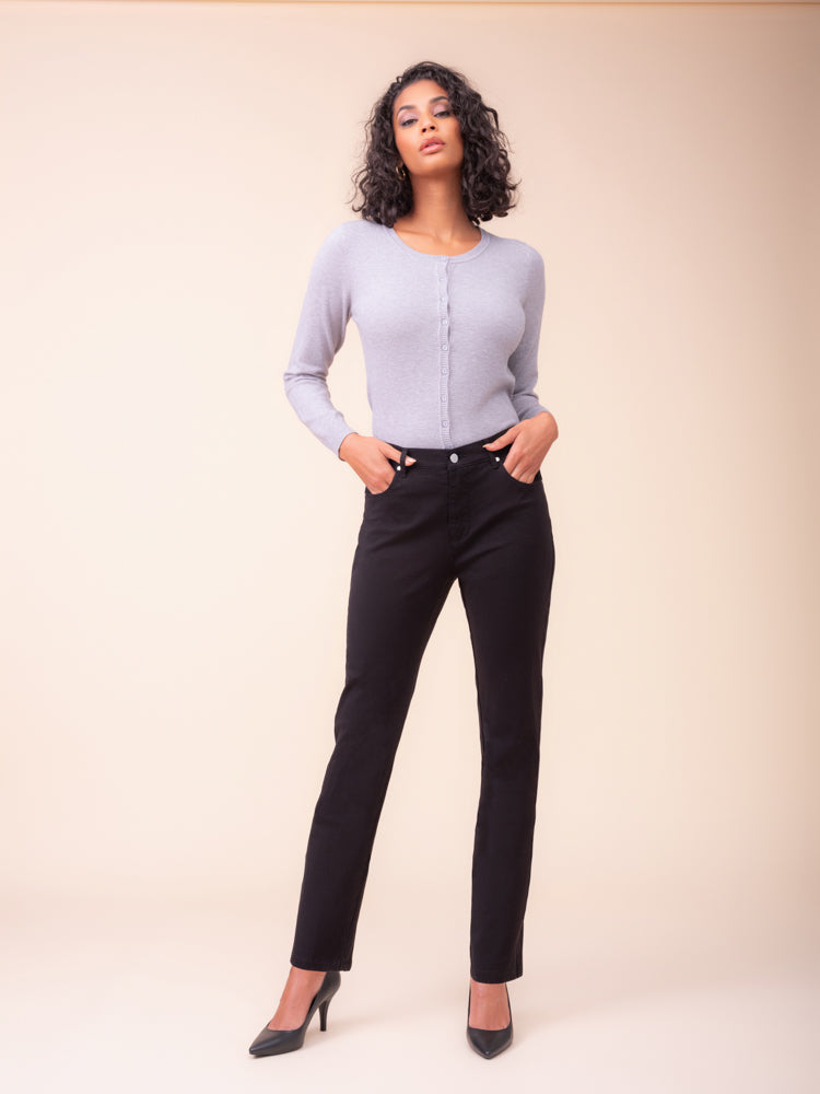 A woman modelling Alison Sheri straight fit black jeans with light lavender long-sleeve knit top against a solid beige studio background. 