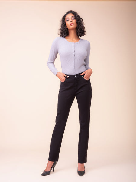 A woman modelling Alison Sheri straight fit black jeans with light lavender long-sleeve knit top against a solid beige studio background. 