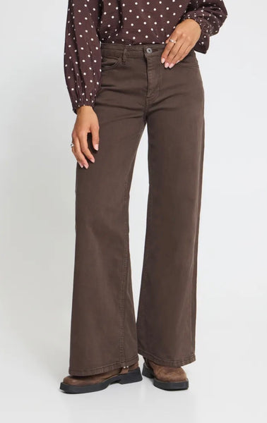 Model wearing Ichi coffee bean jeans with polka dot top and brown flat boots on a white background. 