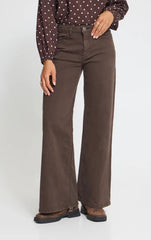 Model wearing Ichi coffee bean jeans with polka dot top and brown flat boots on a white background. 