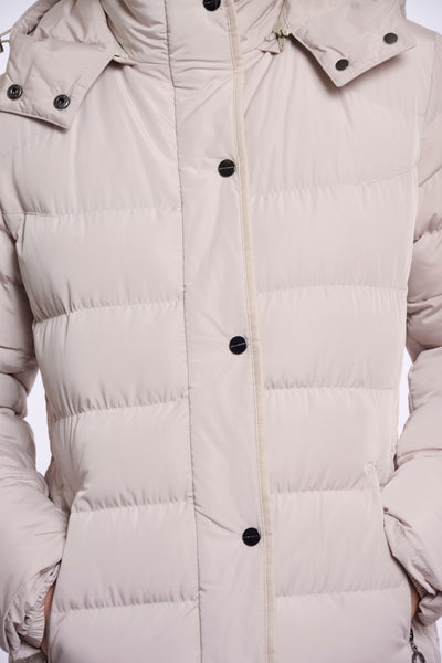 A close up of a light beige padded jacket with horizontal quilting, black snap buttons, and a high collar.