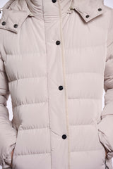 A close up of a light beige padded jacket with horizontal quilting, black snap buttons, and a high collar.