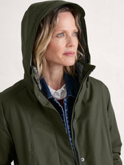 A woman wearing Seasalt olive green hooded jacket with a dark blue denim shirt underneath, photographed against a plain light background.