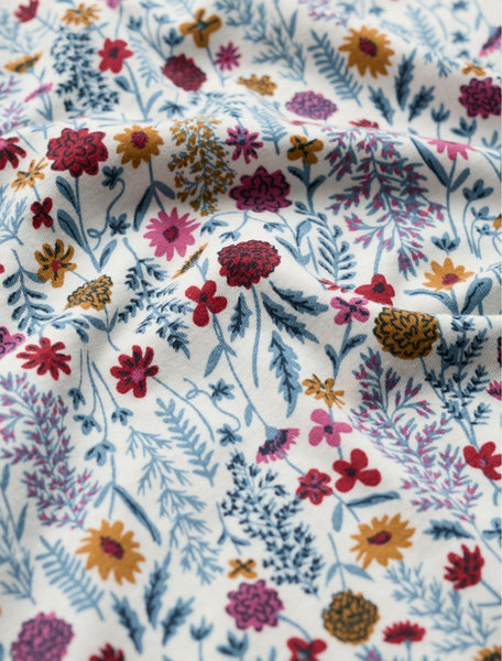 Close up of fabric in floral botanical print, in multicolours red, yellows and blues. 