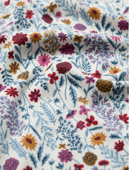 Close up of fabric in floral botanical print, in multicolours red, yellows and blues. 