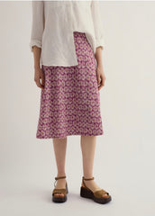 Person wearing a white top and  floral skirt on a plain background.