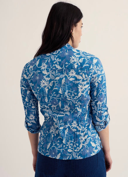 Woman wearing a blue floral patterned shirt against a plain background.