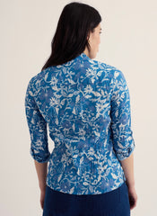 Woman wearing a blue floral patterned shirt against a plain background.