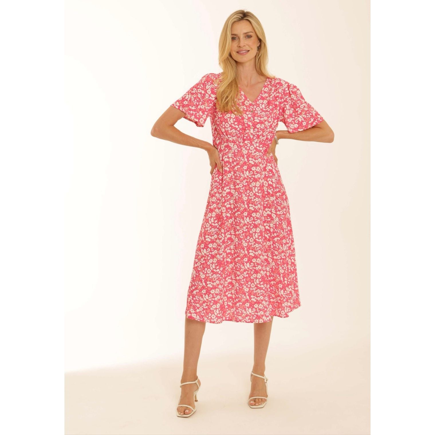 Model wearing a Pomodoro pink midi dress with white heel sandals on a natural background 