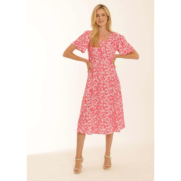 Model wearing a Pomodoro pink midi dress with white heel sandals on a natural background 