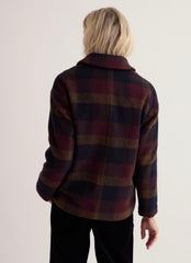 Back profile of woman modelling a check pattern wool Jacket on a white studio background.