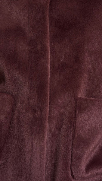 Close up of a plush faux-fur fabric in a deep brown colour, showing the soft texture and a vertical seam.