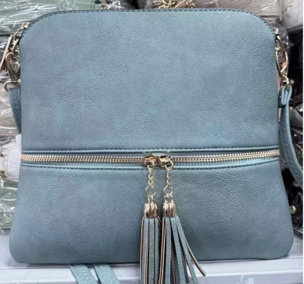 Women’s Blue handbag with gold zipper and tassels on a reflective surface