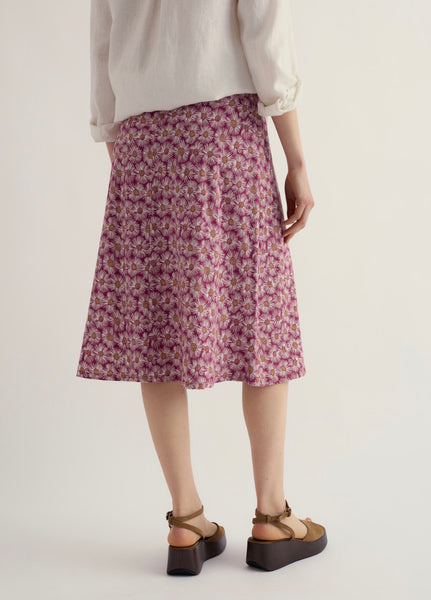 Person wearing a floral skirt on a plain background.