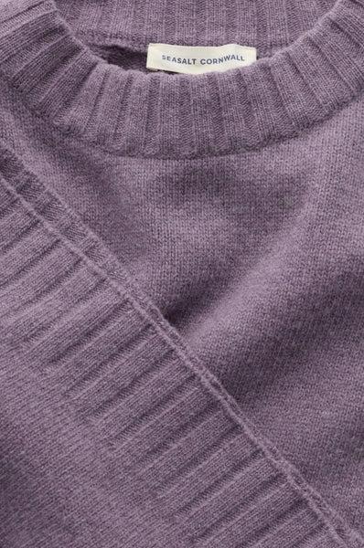 Close-up of a ribbed knit sweater in a muted dusty lavender-purple color, showing the collar and a small white neck label that reads 'SEASALT CORNWALL'.