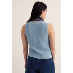 Woman wearing a light blue sleeveless sweater against a plain background.