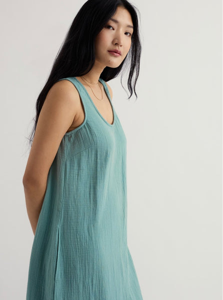 Woman wearing a light green sleeveless dress against a plain background.