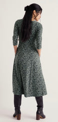 A woman wearing a Seasalt dark green and black floral print midi dress with three-quarter sleeves, shown from the back against a plain light background.
