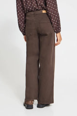 A person shown from the back wearing dark brown wide-leg Ichi pants, a brown polka-dot blouse, and brown boots against a white studio background.