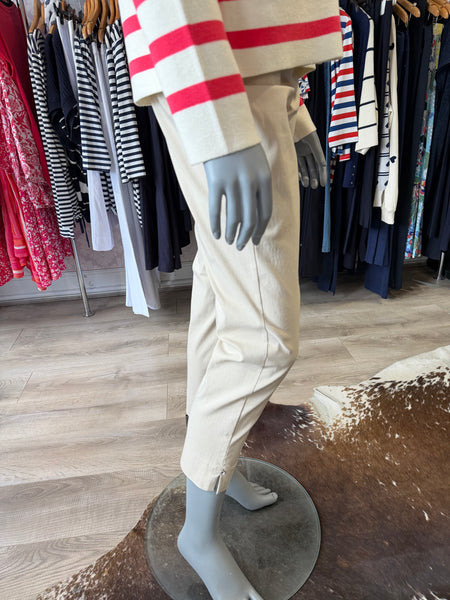 Mannequin wearing a beige trousers with red accents in a clothing store setting.