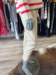 Mannequin wearing a beige trousers with red accents in a clothing store setting.
