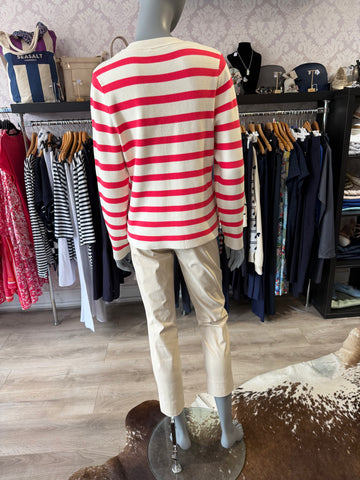 Mannequin wearing a beige trousers with red accents in a clothing store setting.