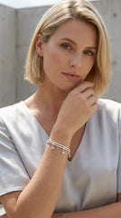 Woman wearing a grey top modelling an Envy silver wraparound bracelet with diamanté moon and star charms. Against an outdoor background.