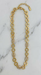 Envy Jewellery gold-tone chain necklace with alternating large oval links and smaller oval links set with clear crystals, displayed on a white marble surface.