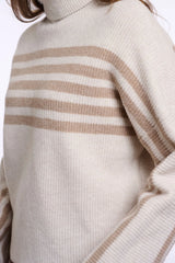 Close-up of a ribbed knit turtleneck sweater in cream with horizontal taupe stripes across the chest and shoulders.