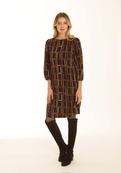 A woman modeling a knee-length Pomodoro dress with three-quarter sleeves, paired with black over-the-knee boots, against a plain white studio background.