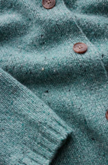 Close-up of a textured knit cardigan in a muted teal-green color with brown buttons.