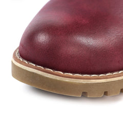 Close-up of a dark burgundy leather boot toe with a tan rubber sole and whipstitching on a white background.